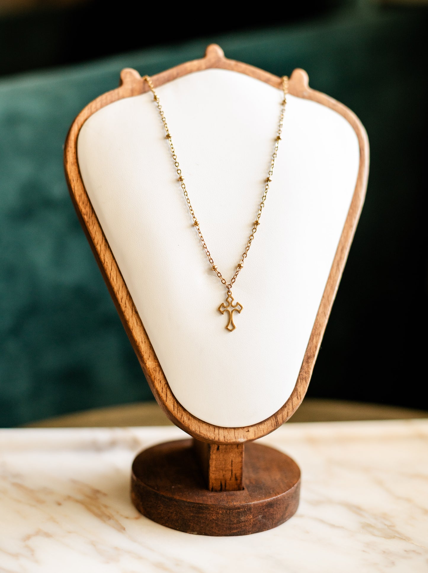 Necklace with a cross pendant on a wooden display stand against a dark background